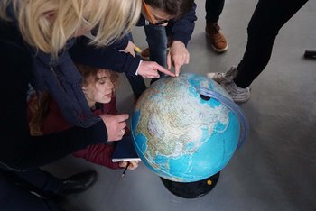 Kinder zeigen auf einen Globus