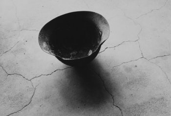 schwarz-weiß Fotografie eines Stahlhelms mit von der Atombombe von Nagasaki eingeschmolzenen Schädelknochen