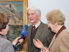 Ein älteres Paar wird vor einem Gemälde interviewt