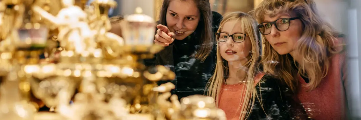 Zwei Erwachsene und ein Kind betrachten ein Objekt