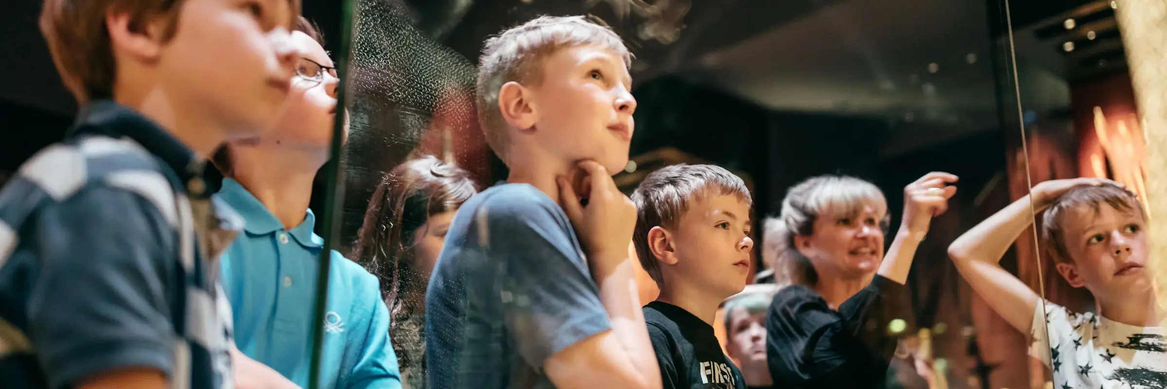 Eine Kindergruppe stehen vor einem Museumsexponat 