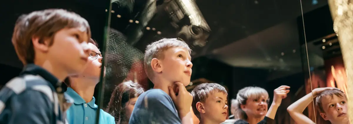 Eine Kindergruppe stehen vor einem Museumsexponat 