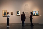 Ausstellungsansicht "Paula Modersohn-Becker und Edvard Munch. Die großen Fragen des Lebens" drei Personen schauen sich eine Wand mit Bildern an