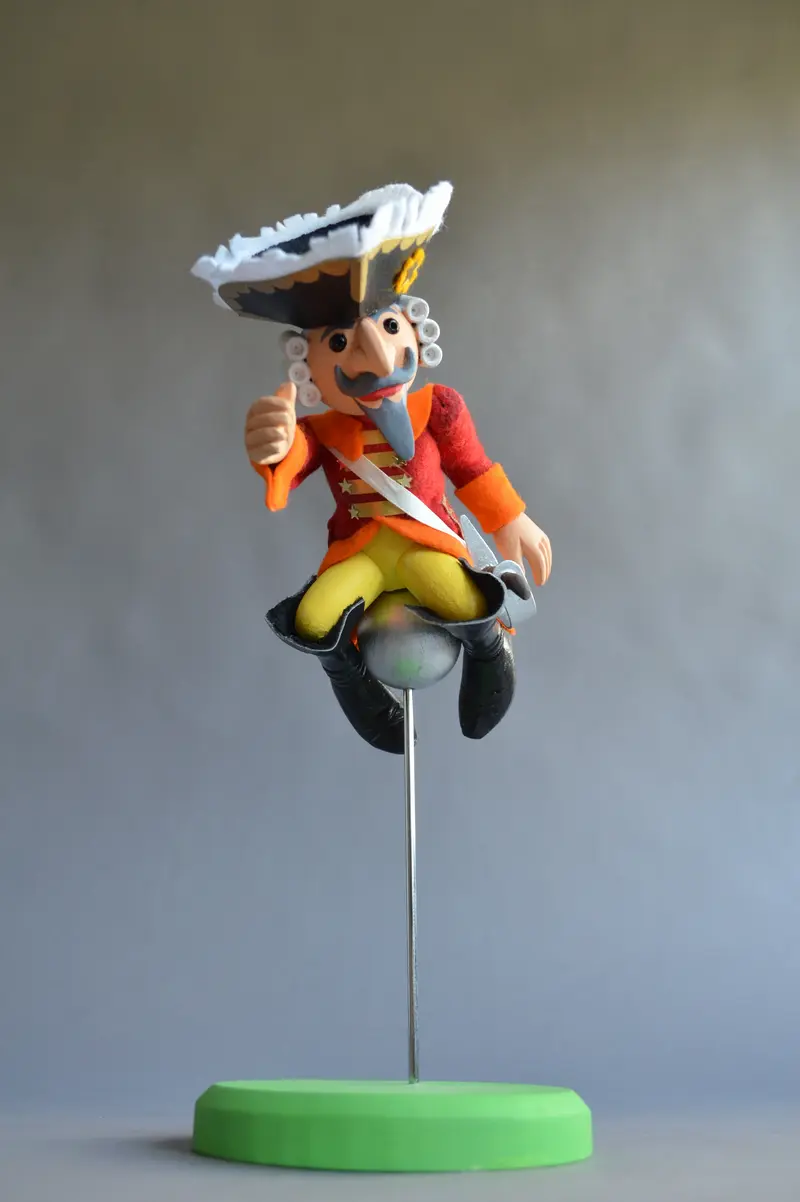 Ansicht einer männlichen Holzfigur, die auf einer Kanonenkugel reitet