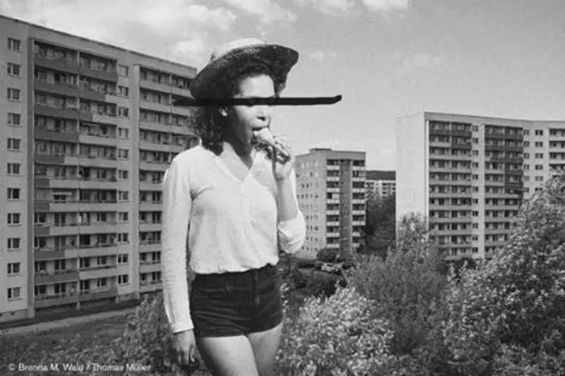 ein Mädchen isst ein Eis vor einer Plattenbausiedlung
