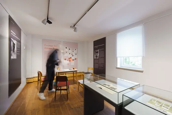 Ausstellungsraum mit einer Person neben Stühlen