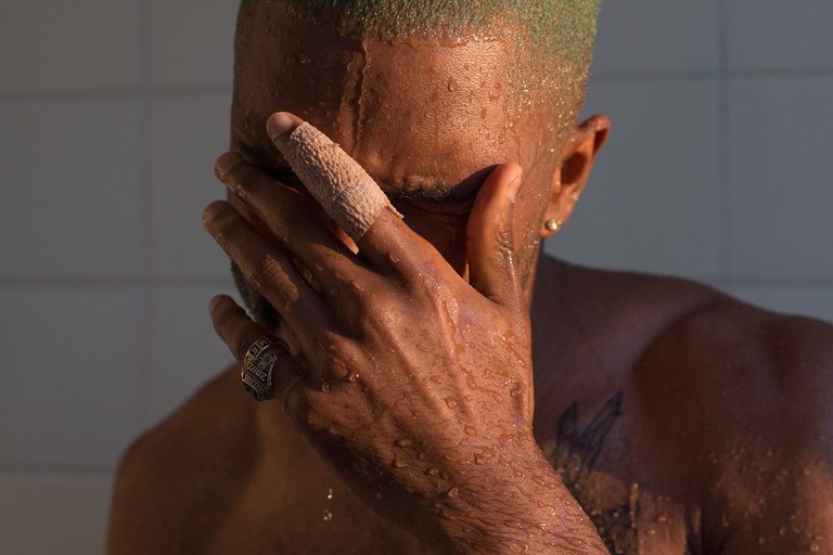 Ein Mann in der Dusche bedeckt sein Gesicht mit seiner Hand
