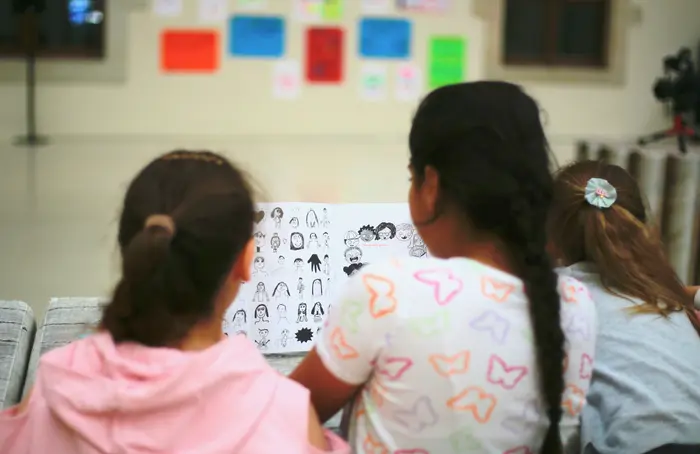 Drei Mädchen, von hinten fotografiert, lesen gemeinsam ein Buch