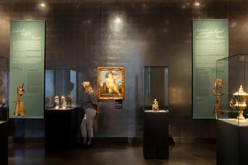 Besucherinnen schauen sich Kunstwerke in einer Vitrine an
