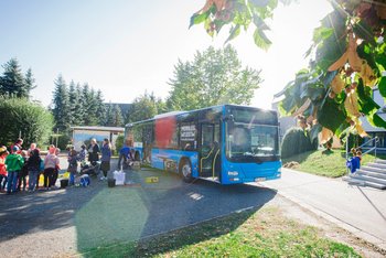 ein Bus in der Sonne vor einer Schule