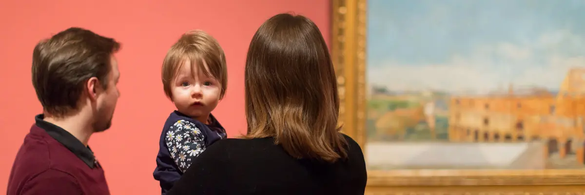 Elternpaar mit Kind auf dem Arm, betrachten ein Gemälde