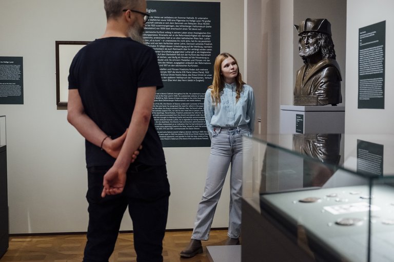 Mann und Frau betrachten eine Statue im Ausstellungsraum
