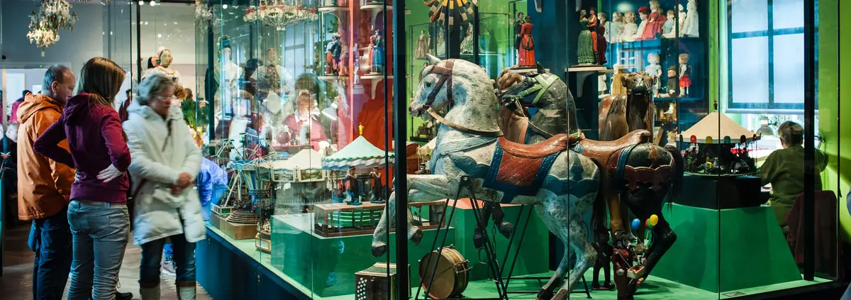 Besucher schauen sich eine große Vitrine mit Objekten an