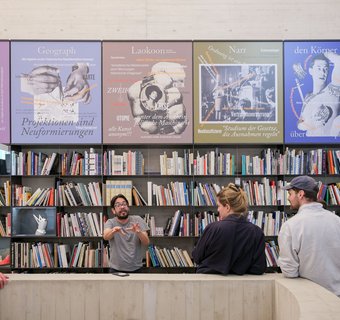 Bücherwand mit mehreren Personen davor
