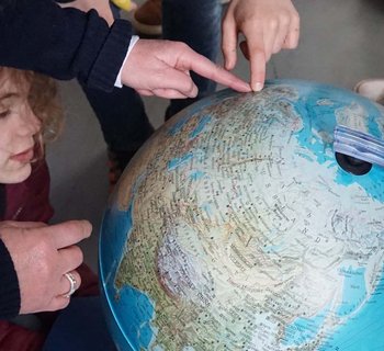 Kinder zeigen auf einen Globus