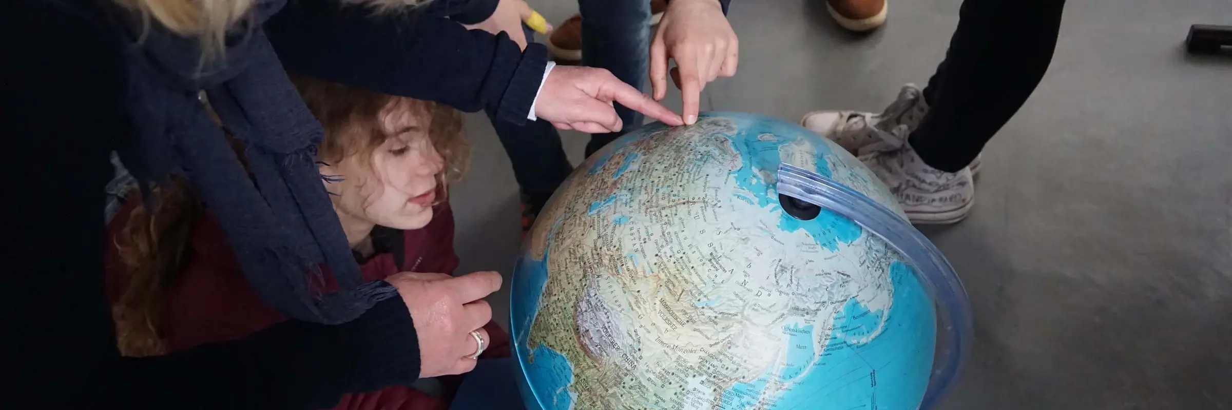 Kinder zeigen auf einen Globus