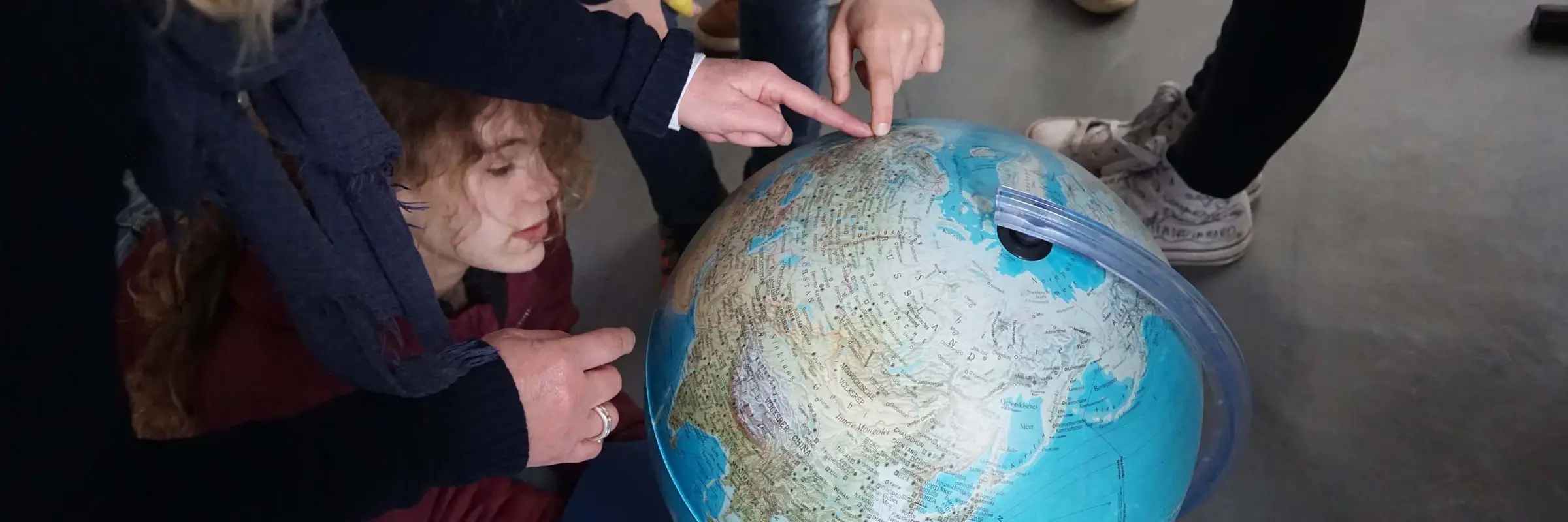 Kinder zeigen auf einen Globus