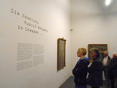 Besucher lesen einen Wandtext in einer Ausstellung