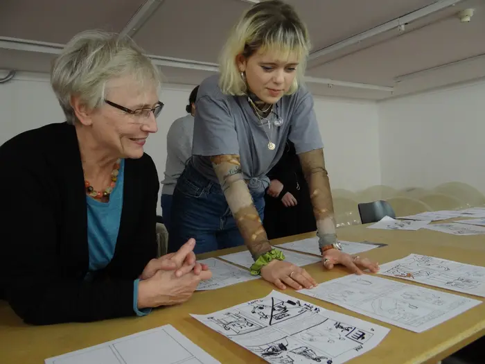 Zwei Personen betrachten Zeichnungen an einem Tisch