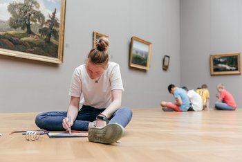 Kinder sitzen vor einer Installation, Pädagoge erzählt dazu