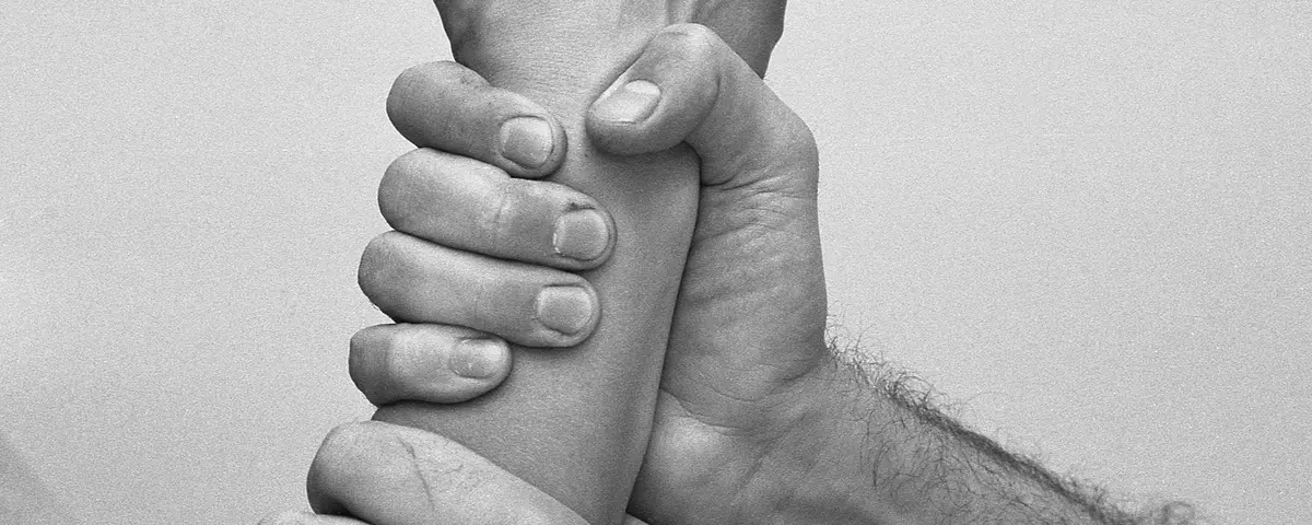 ein Unterarm, der von zwei Händen festgehalten wird