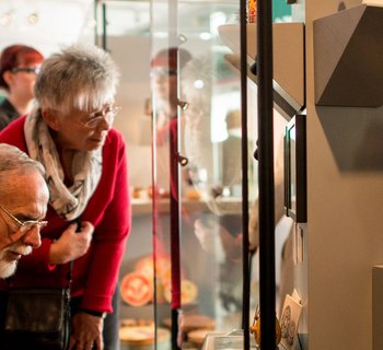 Besucher betrachten kleine Holzfiguren