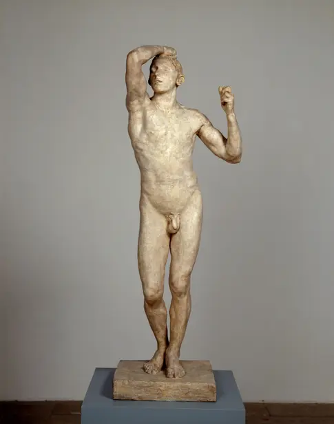 Skulptur eines nackten Mannes, eine Hand am Kopf