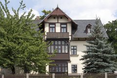 Haus mit zwei Bäumen und Gartenzaun davor