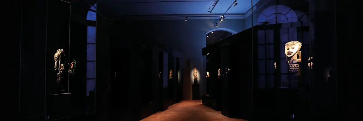 dunkler Raum mit angeleuchteten Objekten in Vitrinen