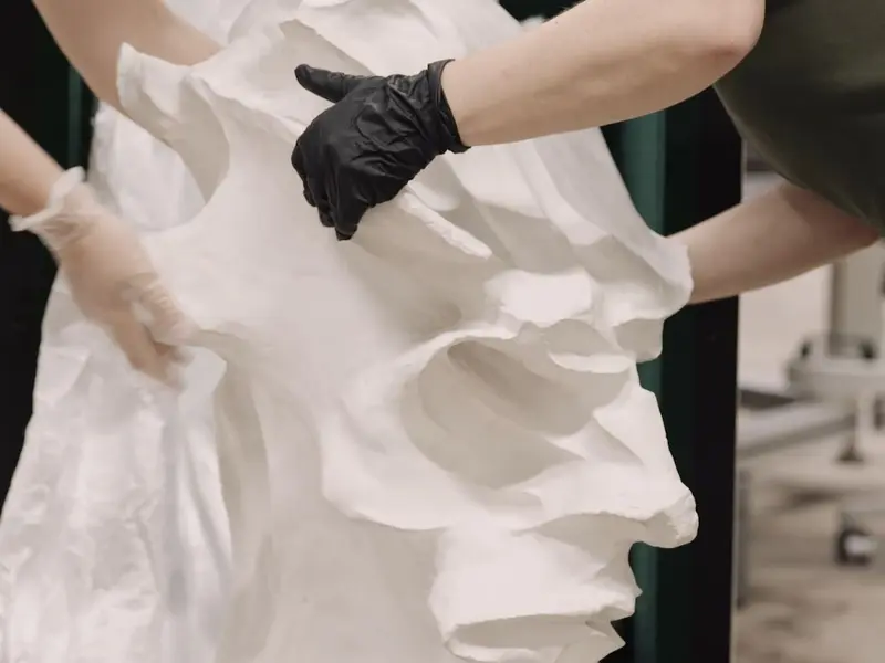 Hände in Handschuhen untersuchen ein großes Stück Papier