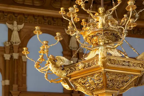 Detailansicht eines goldenen Kronleuchters mit Engelfiguren