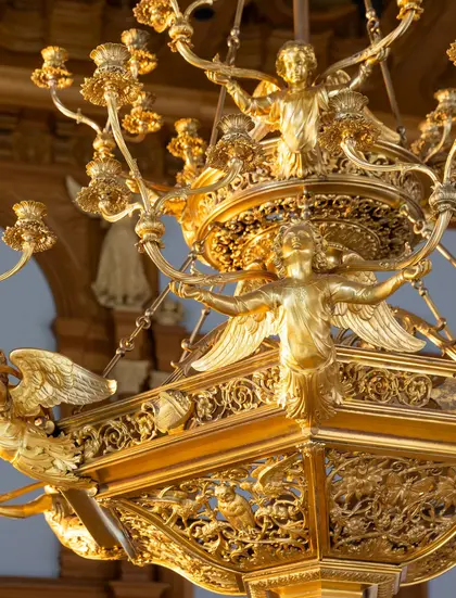 Detailansicht eines goldenen Kronleuchters mit Engelfiguren