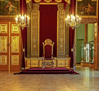 festlicher Raum mit prunkvollen goldenen Elementen und einem Thron