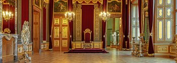 festlicher Raum mit prunkvollen goldenen Elementen und einem Thron