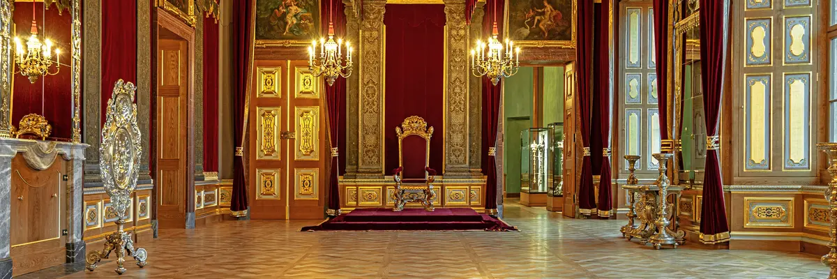 festlicher Raum mit prunkvollen goldenen Elementen und einem Thron