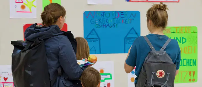 Eltern und Kinder schauen selbstgemachte Plakate an