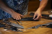 Nils Bergauer, Handschuhmacher, Schneeberg Hände an einem Tisch voll mit Stoffen und einer großen Schere