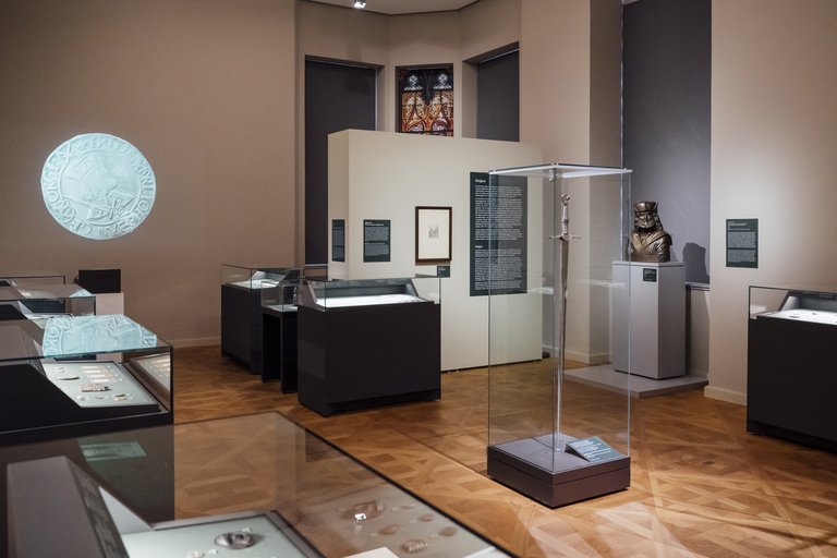 Ausstellungsraum mit Vitrinen und einer Wandprojektion