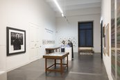Ausstellungsansicht "20 Jahre Gerhard Richter Archiv" Raumansicht mit Vitrinen und großem Foto an der Wand, zwei Frauen betrachten Vitrine