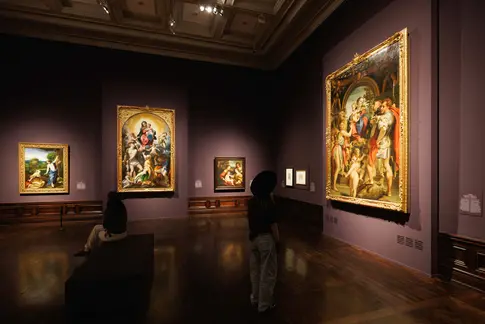 Besucher in einer Ausstellung mit großen Gemälden