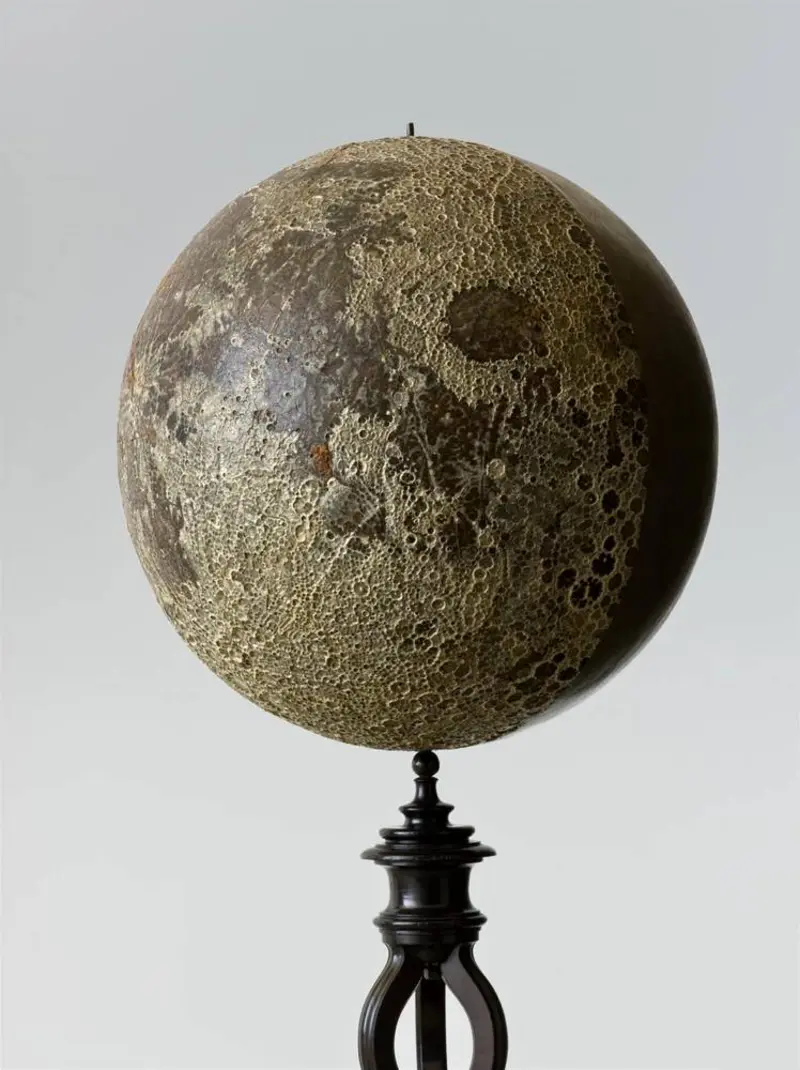 plastisches Modell einer Mondkugel auf Holzstelze