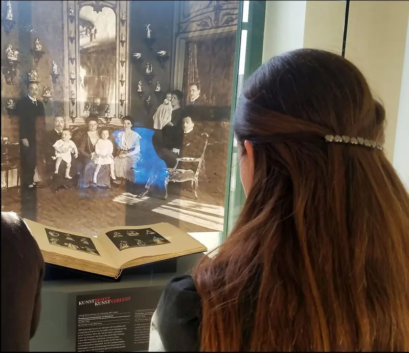 Rückenansicht einer Person vor einer Ausstellungsvitrine