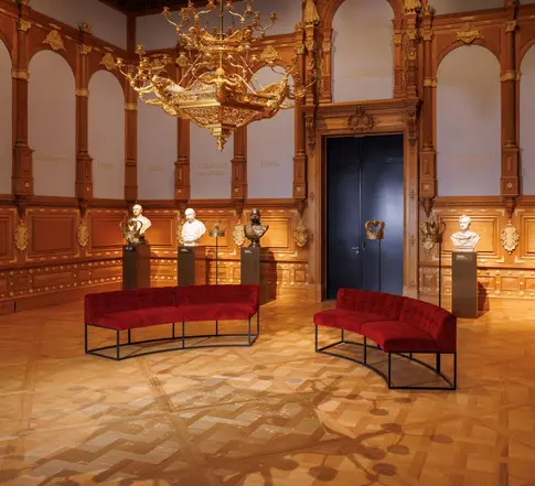 rotes Sofa, im Hintergrund Büsten von Männern