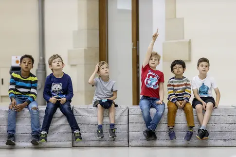 Kinder sitzen auf einer Bank im Museum