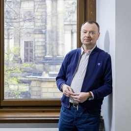 Mann an einer Wand vor einem Fenster lehnend