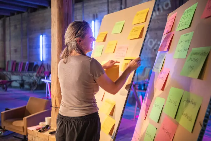 Eine Frau vor zwei Pinnwänden mit bunten Post-Its