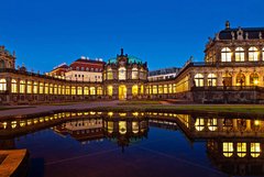 Die Außenansicht der Porzellansammlung spiegelt sich bei Nacht in einem Brunnen