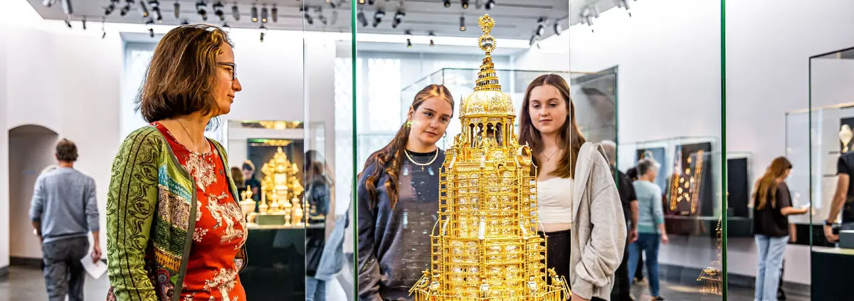 Besucherinnen betrachten eine Vitrine mit einem goldenen Ausstellungsstück