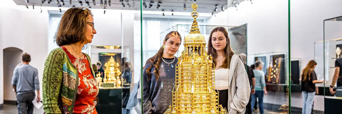 Besucherinnen betrachten eine Vitrine mit einem goldenen Ausstellungsstück