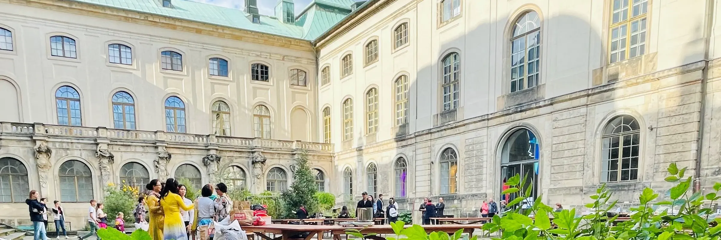 Innenhof eines historischen Gebäudes mit Menschen und Pflanzen